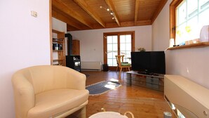 Ein Wohnzimmer mit einem beigefarbenen Sofa, einem Fernseher und einem Holzboden.