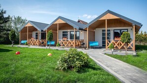 Ein modernes Hotel im Bungalow-Stil mit drei Einheiten, jeweils mit einem Balkon und einem kleinen Garten.