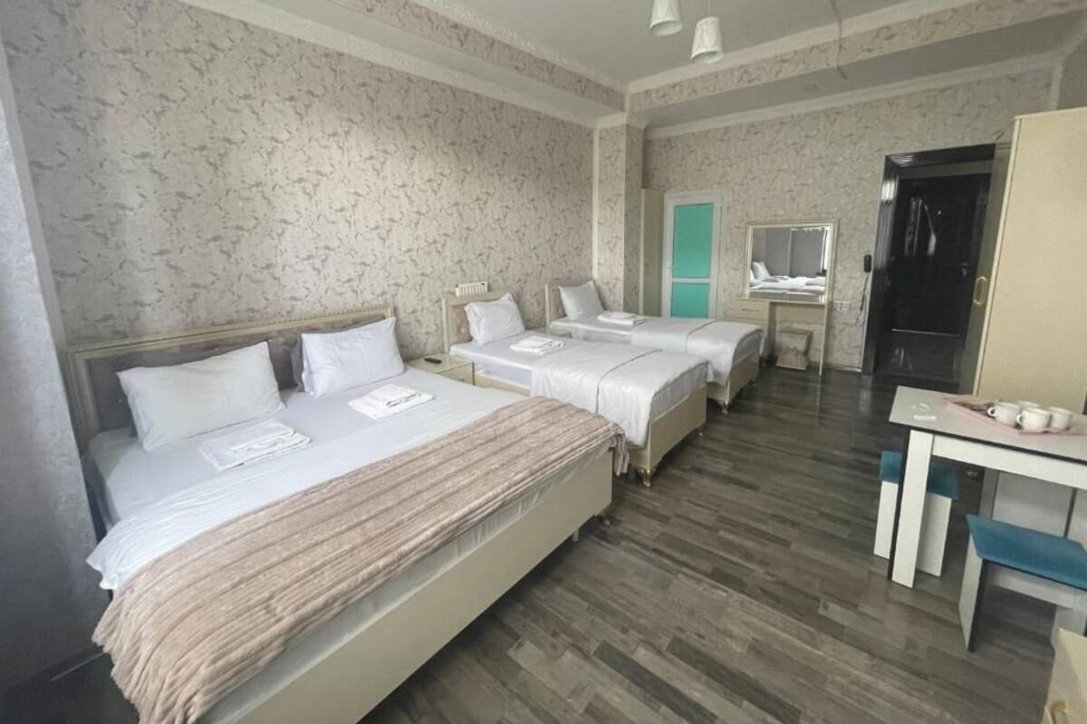 Ein Hotelzimmer mit zwei Betten, einem Schreibtisch, einem Spiegel und einem Kleiderschrank.