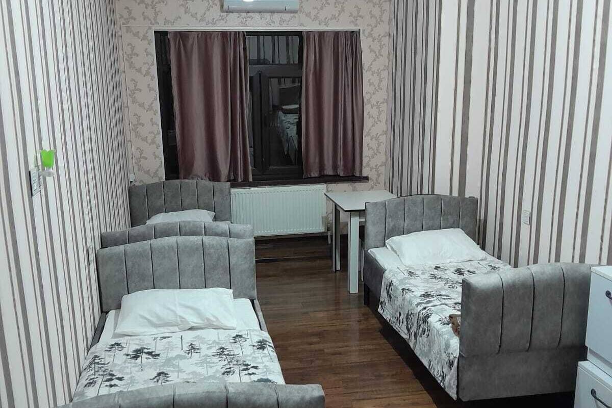 Ein kleines Hotelzimmer mit zwei Einzelbetten, einem Tisch und einer Heizung.