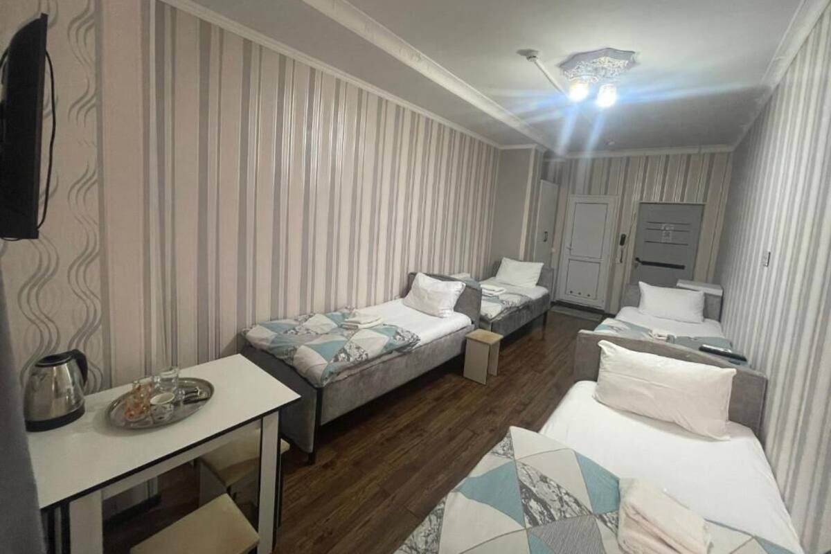 Ein Zimmer mit zwei Einzelbetten, einem kleinen Tisch mit Wasserkocher und einem an der Wand befestigten Fernseher.