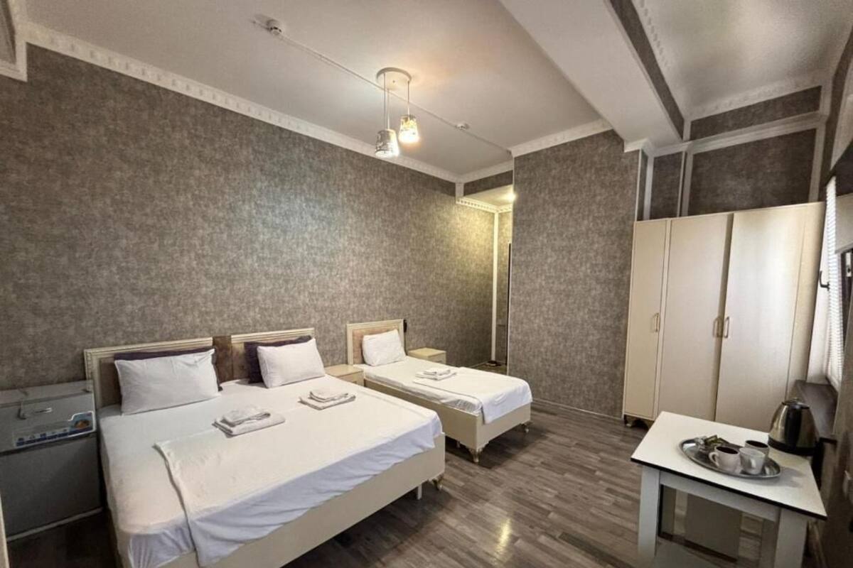 Ein Hotelzimmer mit zwei Betten, einem Schreibtisch mit Tablett und einem Kleiderschrank.