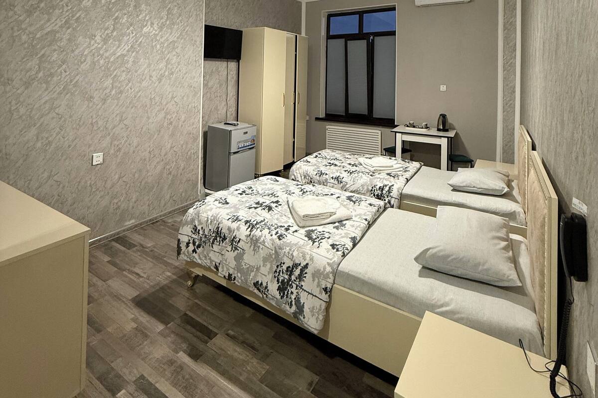 Ein modernes Schlafzimmer mit zwei Betten, einem Schreibtisch und einem Fenster.