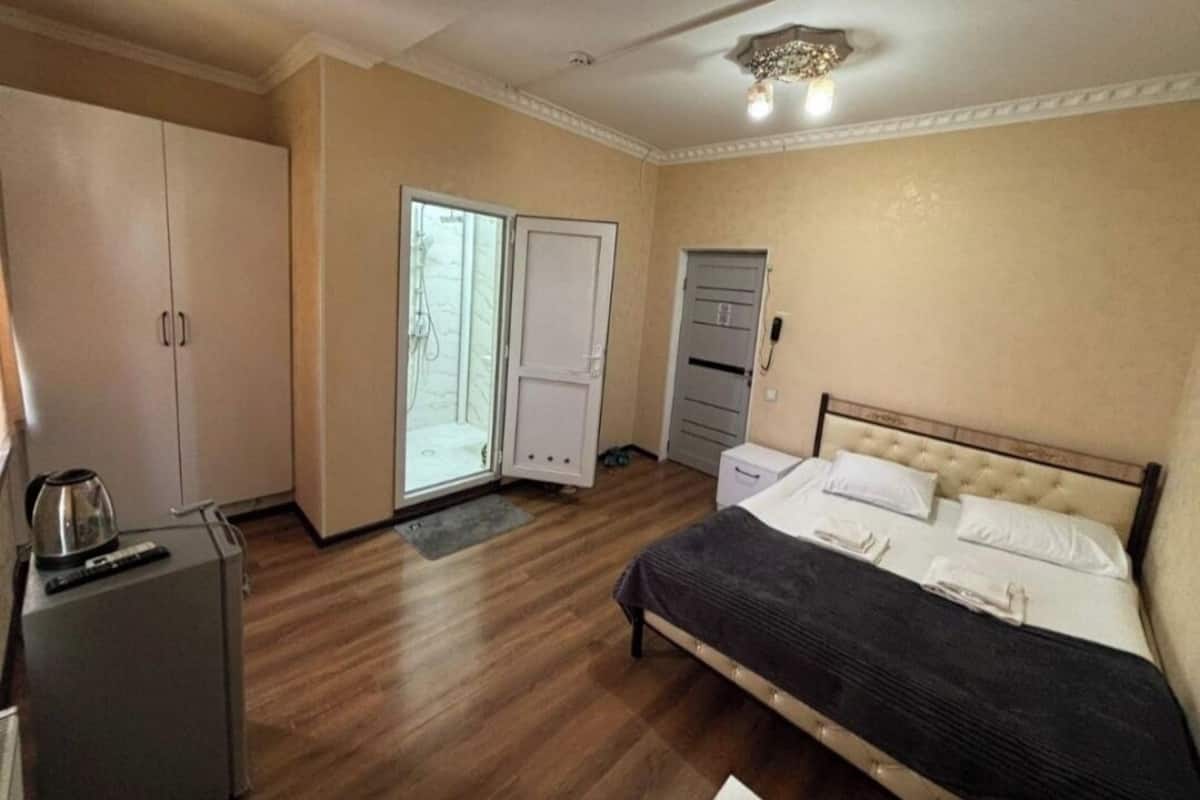 Ein Schlafzimmer mit Bett, Kleiderschrank und Schreibtisch mit Wasserkocher.