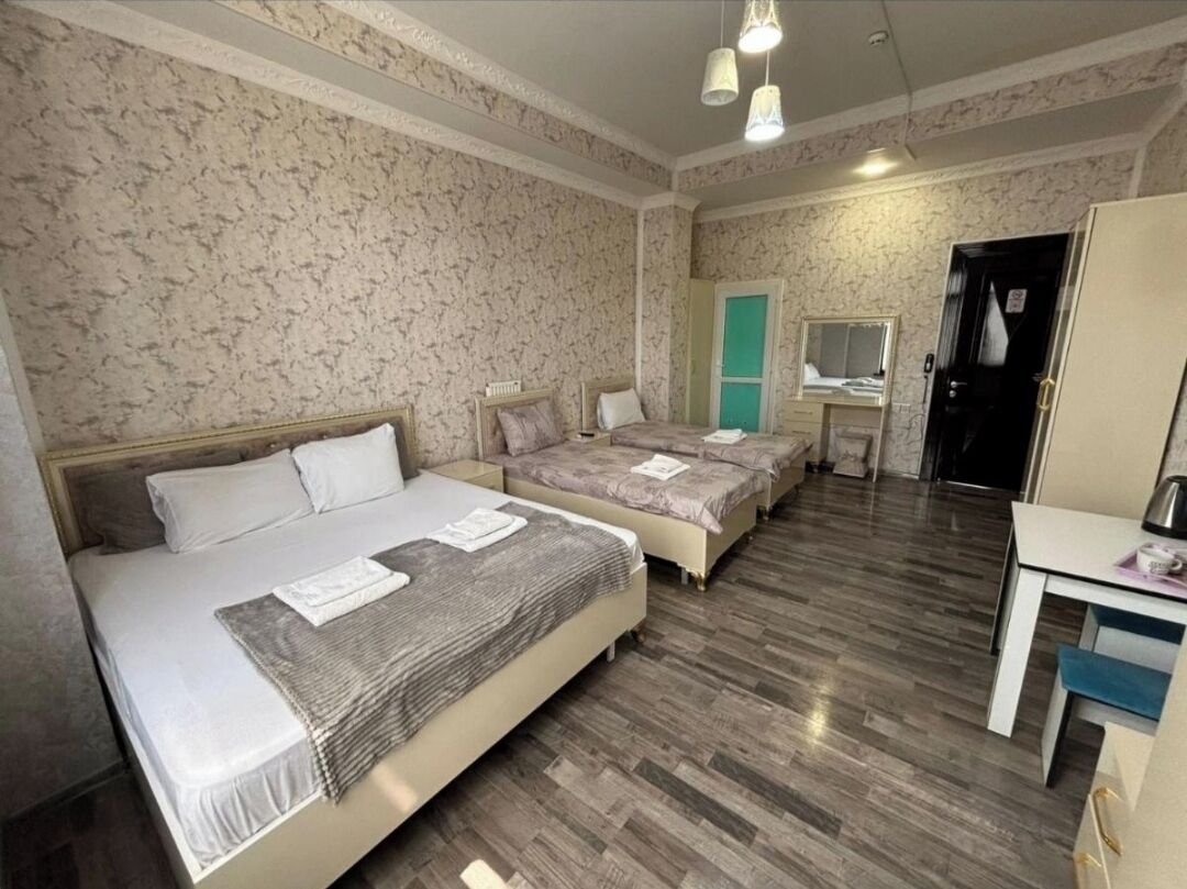 Een hotelkamer met een groot bed, een kleiner bed, een bureau en een kledingkast.