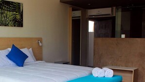 Une chambre d’hôtel avec un lit, une table de chevet avec des serviettes, une lampe fixée au mur et un tableau.