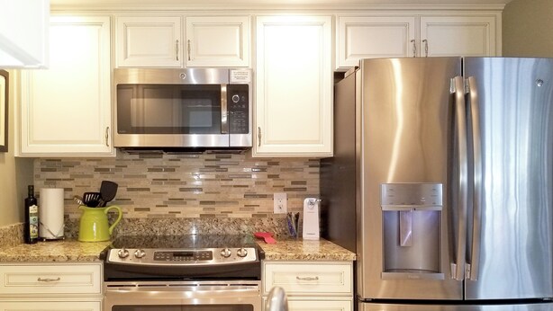 A kitchen with stainless steel appliances, a granite countertop, and white cabinetry. - SALTWATER SMILES 3/2-HEATED POOL HOME 5 MILES FROM AMI WITH GAMES AND PING PONG. (BRADENTON,)