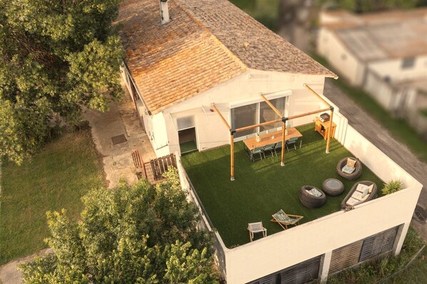 Une maison moderne avec un toit en pente, un patio couvert agrémenté de mobilier d’extérieur et une pelouse bien entretenue.