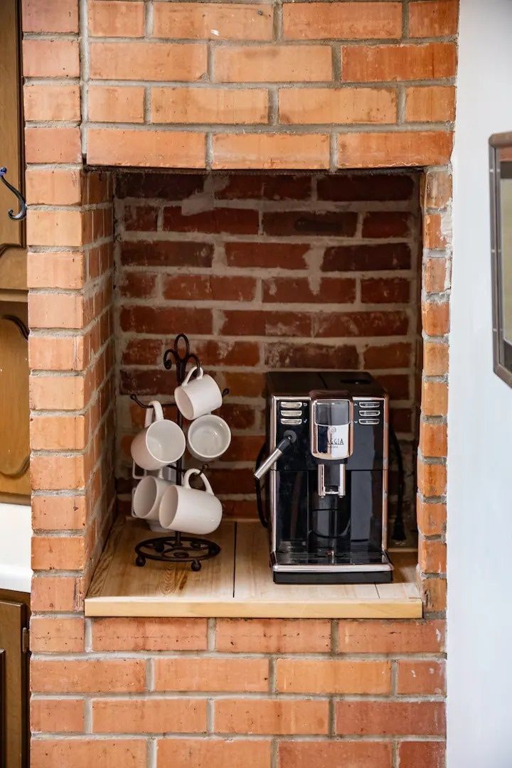 Une cheminée en briques avec une machine à café et un porte-tasses.
