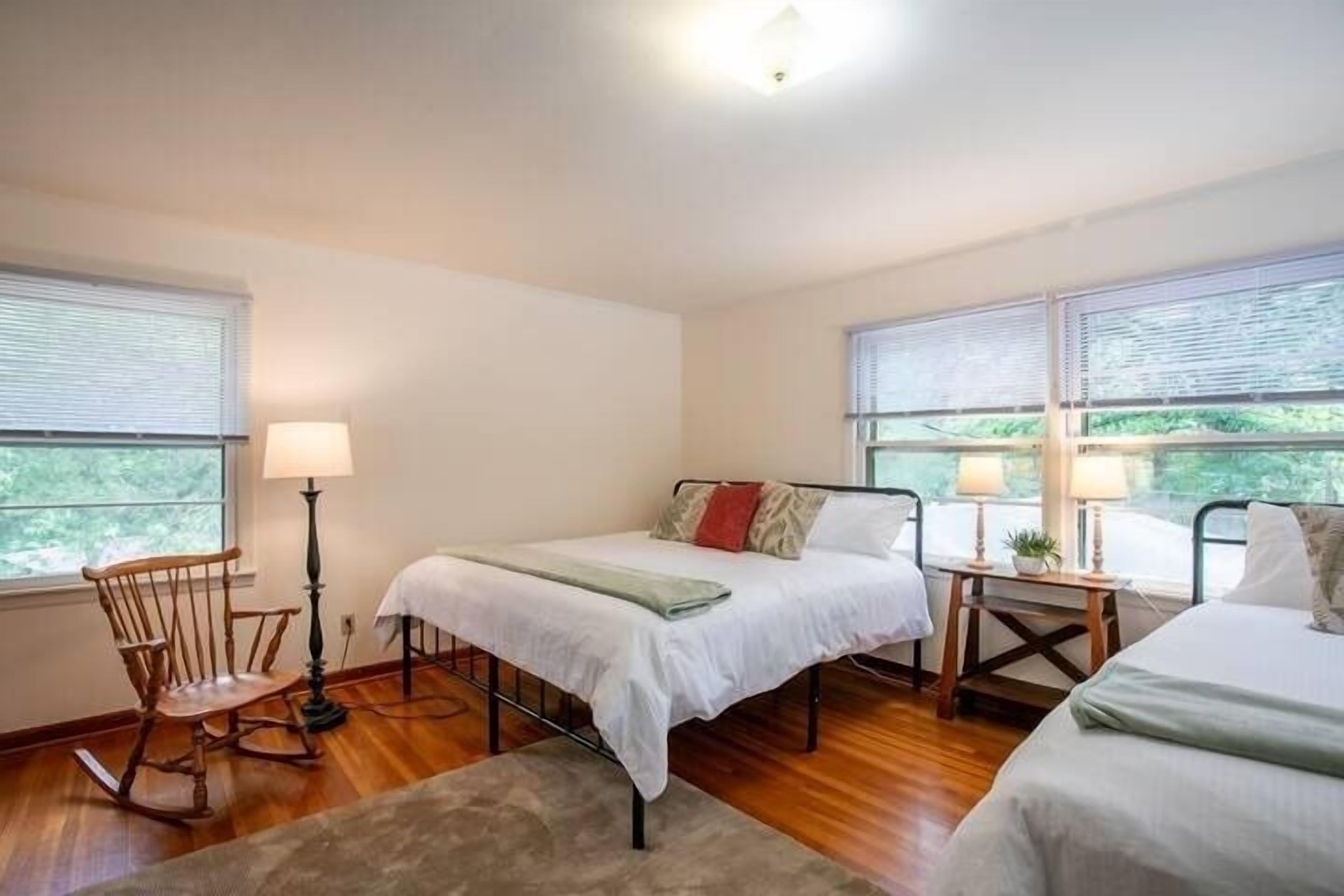Une chambre à coucher avec un lit simple, un fauteuil à bascule et une petite table avec une lampe.
