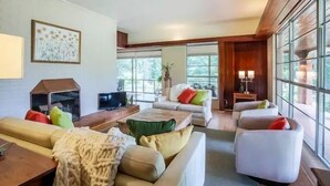 Un salón comedor amplio con un gran ventanal, chimenea y un espacio de descanso confortable.