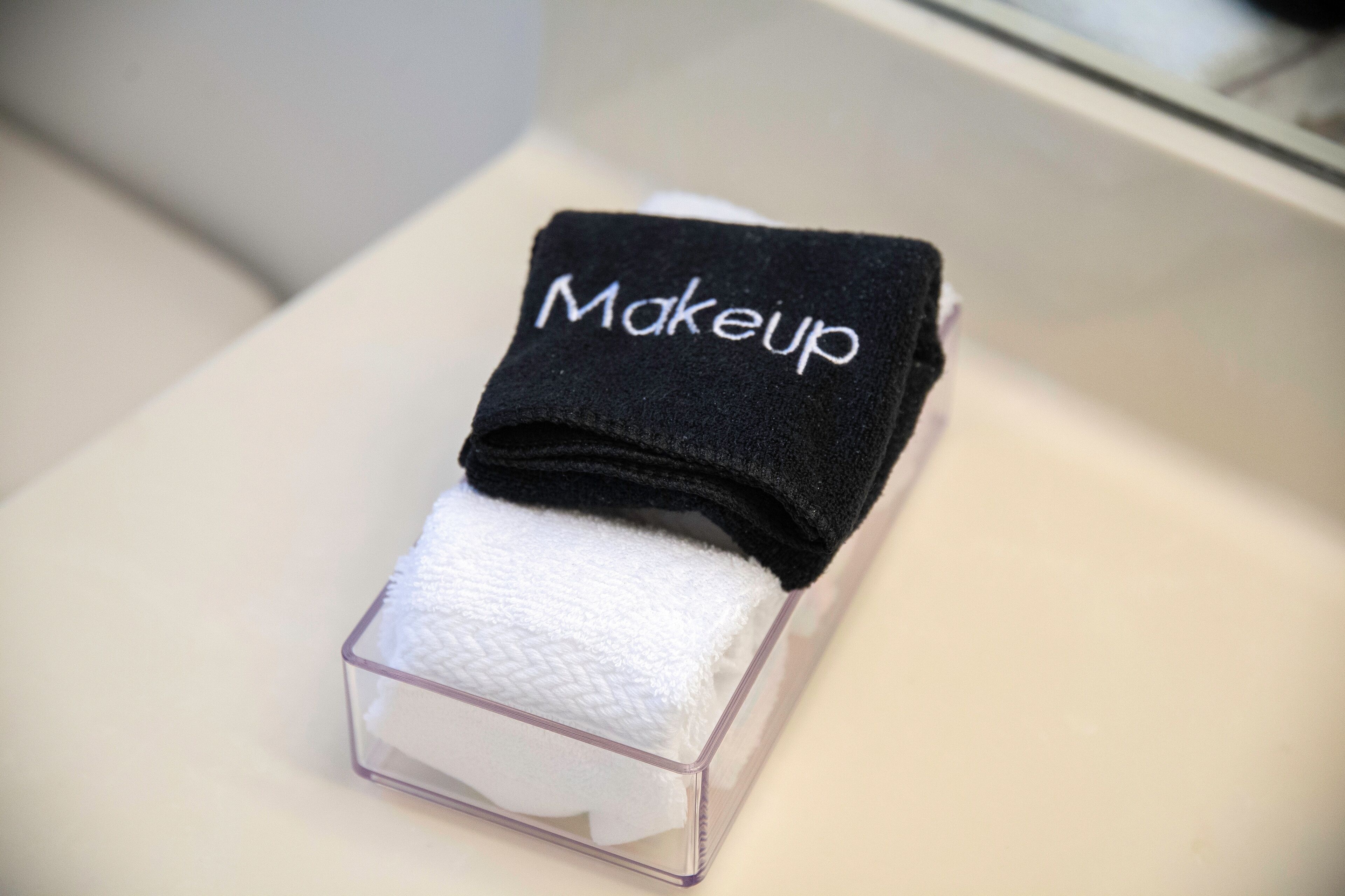 Estuche de maquillaje de plástico transparente con una toalla negra etiquetada 'Makeup' encima.