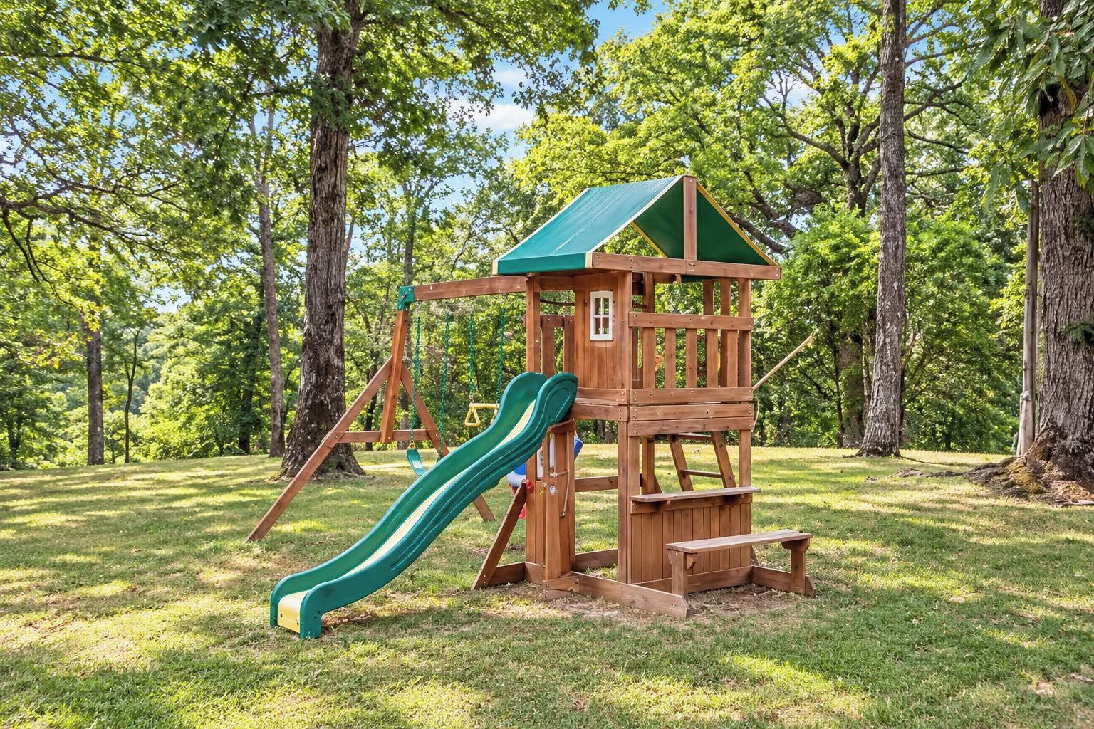 A wooden playground structure with a slide and swings in a grassy park area.