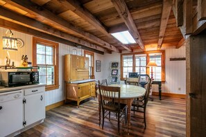 A rustic kitchen with wooden beams, a dining table, chairs, and a microwave. - The Lil' Sipp-4mi to Sq+Campus-Velvet Ditch Villas (Oxford)