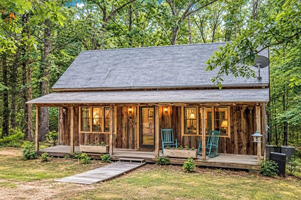 Une cabane en bois avec une véranda, deux chaises et une antenne parabolique.