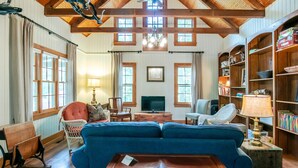A cozy living room with a blue sofa, wooden bookshelves, and a television. - The Lil' Sipp, 2BR Cabin by Velvet Ditch Villas (Oxford)