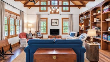 Un salón espacioso con un amplio sofá azul, estanterías de madera, un televisor y una chimenea.