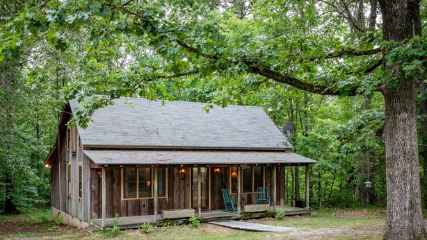 A rustic cabin with a porch, surrounded by trees. - The Lil' Sipp, 2BR Cabin by Velvet Ditch Villas (Oxford)
