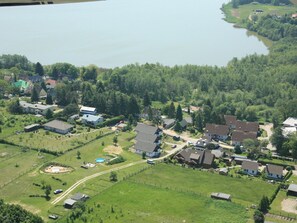 An aerial view of a residential area with houses, a swimming pool, and a lake. - Ferienhaus in Bansin am See (Heringsdorf)
