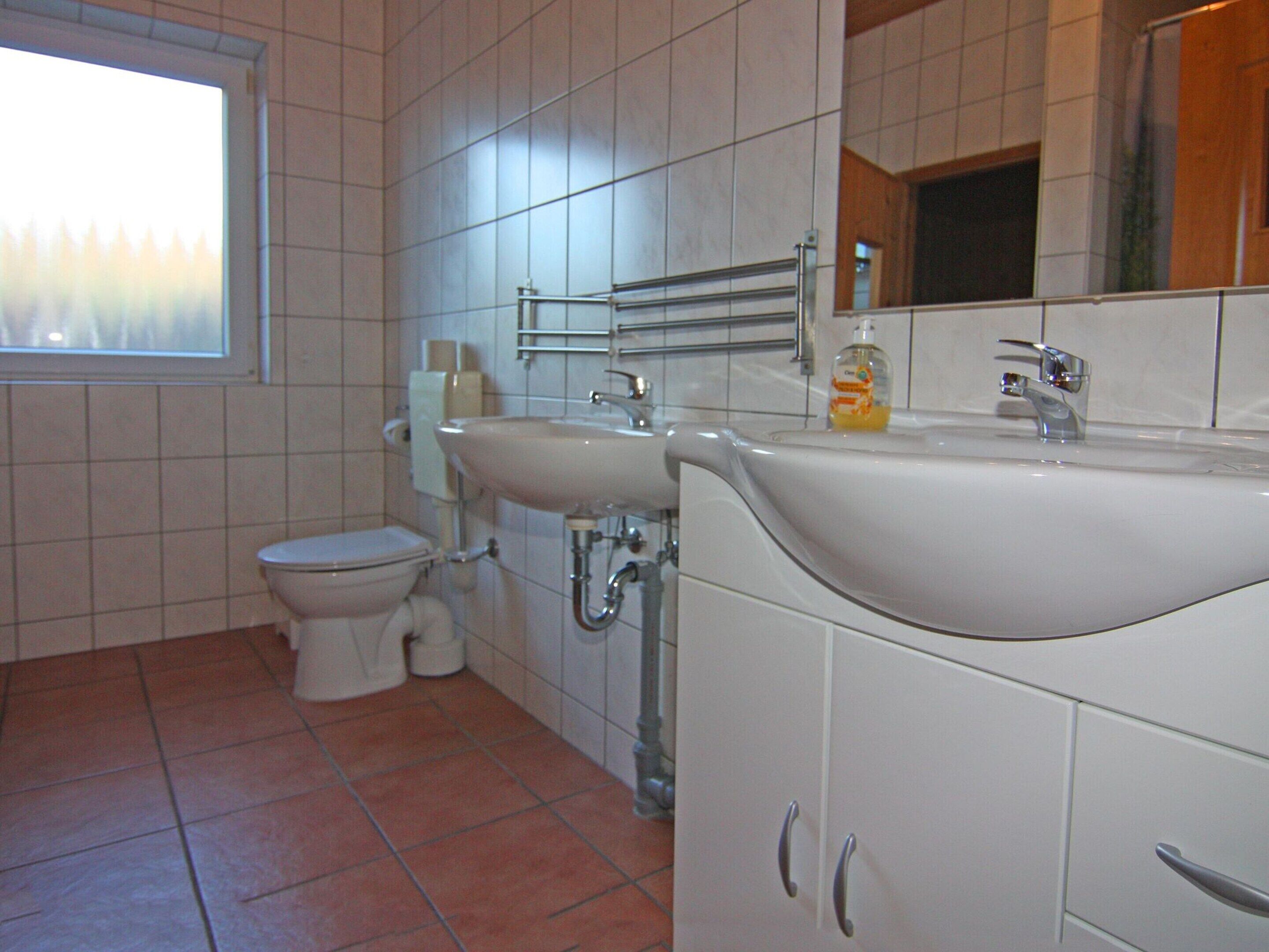 A bathroom with a toilet, sink, and mirror.