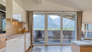 A modern kitchen with wooden accents and a large sliding glass door leading to a balcony with a mountain view. - Holiday Home in Neukirchen With Mountain Views (Neukirchen am Grossvenediger)