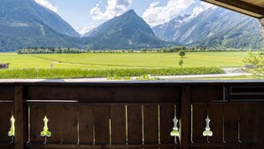 A view from a wooden balcony overlooking a green valley with mountains in the background. - Holiday Home in Neukirchen With Mountain Views (Neukirchen am Grossvenediger)