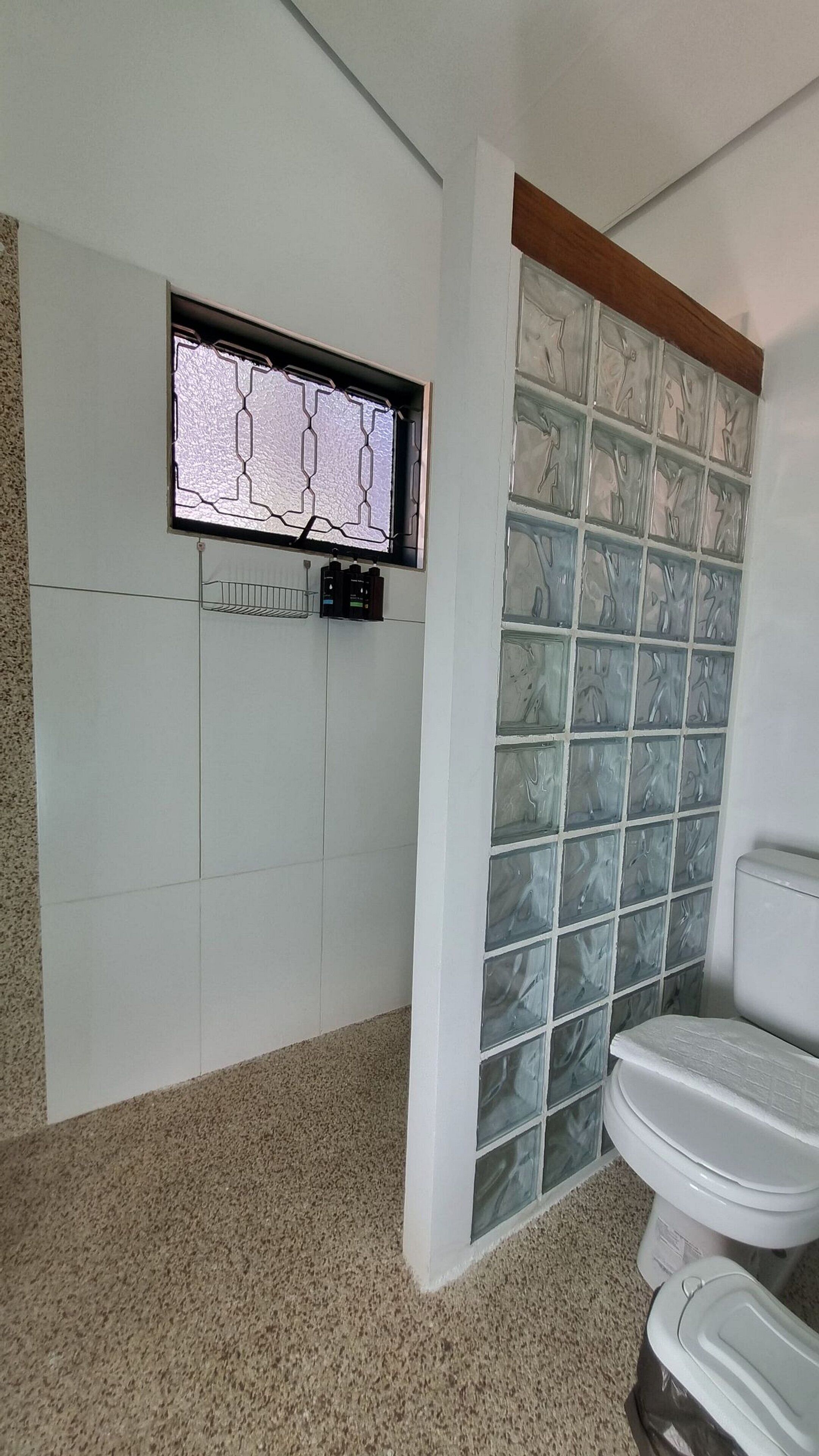 A bathroom with a toilet, a sink, and a window with a geometric pattern.
