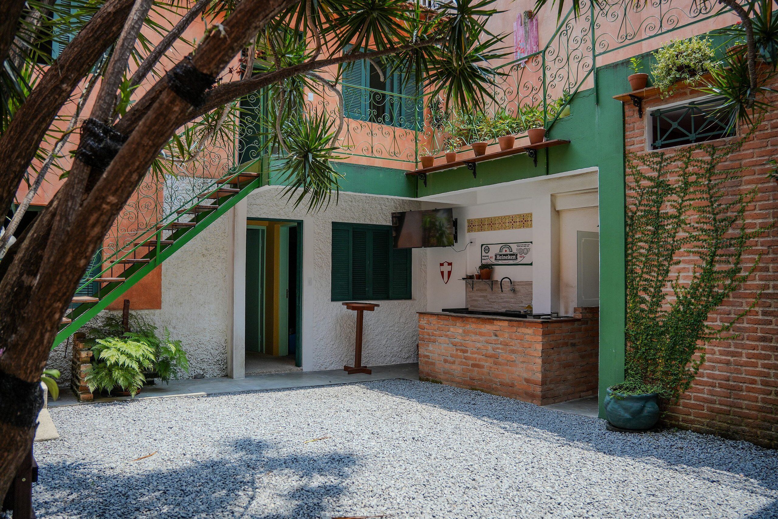 A courtyard with a gravel ground, a brick wall, a green door, and a small table.