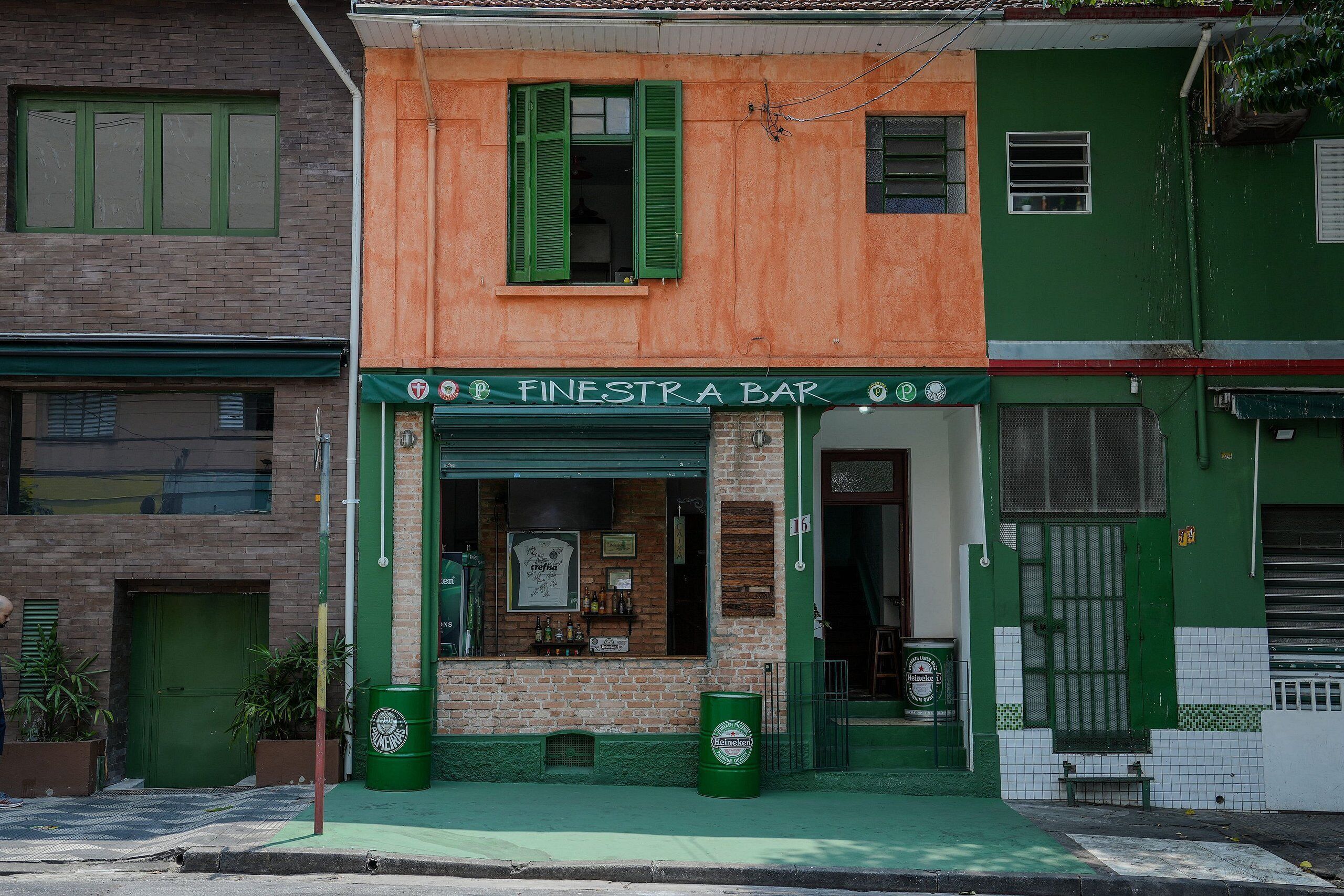 A bar with a green awning, a brick facade, and a green door.