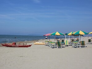 A beach with rows of beach chairs and umbrellas, a rowboat, and a clear view of the sea. - Holiday House in Versilia With Pool & Beaches (Camaiore)
