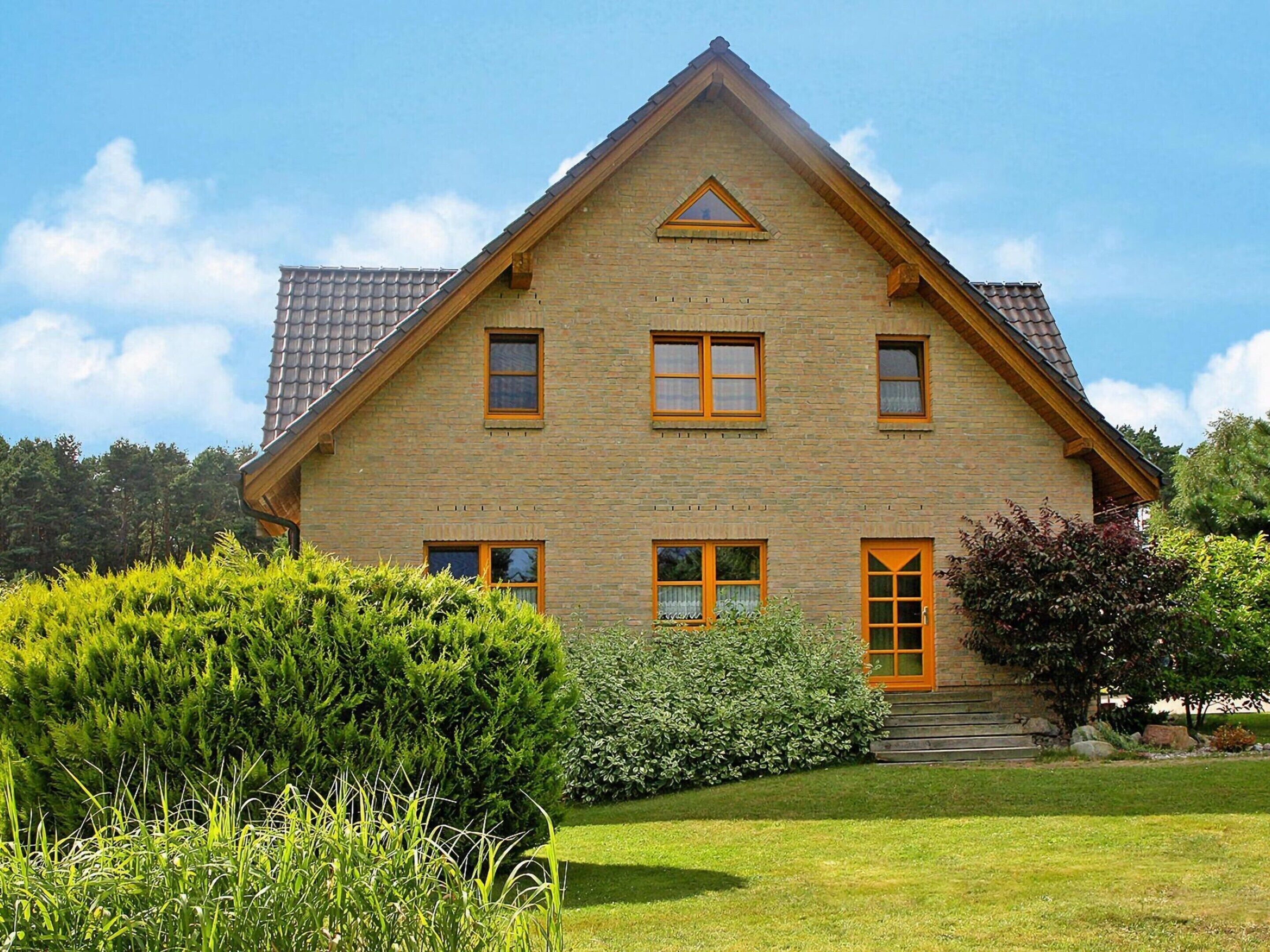 Een huis met twee verdiepingen, een puntige kap, veel ramen en een verzorgd gazon.