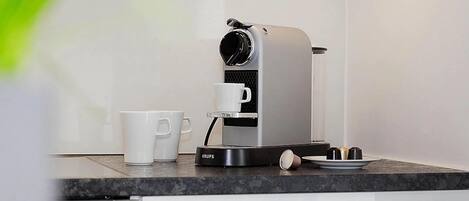 Una cocina moderna con una cafetera, una taza blanca y un plato en la encimera.