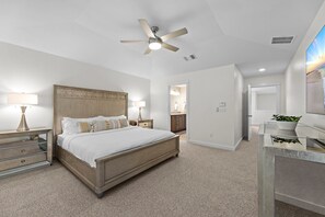 A bedroom with a bed, bedside tables, a ceiling fan, and a view of the bathroom. - Large South Austin Home with a Pool (Austin)