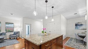 A modern kitchen with granite countertops, wooden cabinets, and pendant lighting. - Large South Austin Home with a Pool (Austin)
