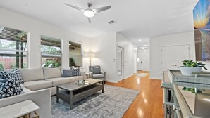 A modern living room with a sofa, armchair, coffee table, and a ceiling fan. - Large South Austin Home with a Pool (Austin)