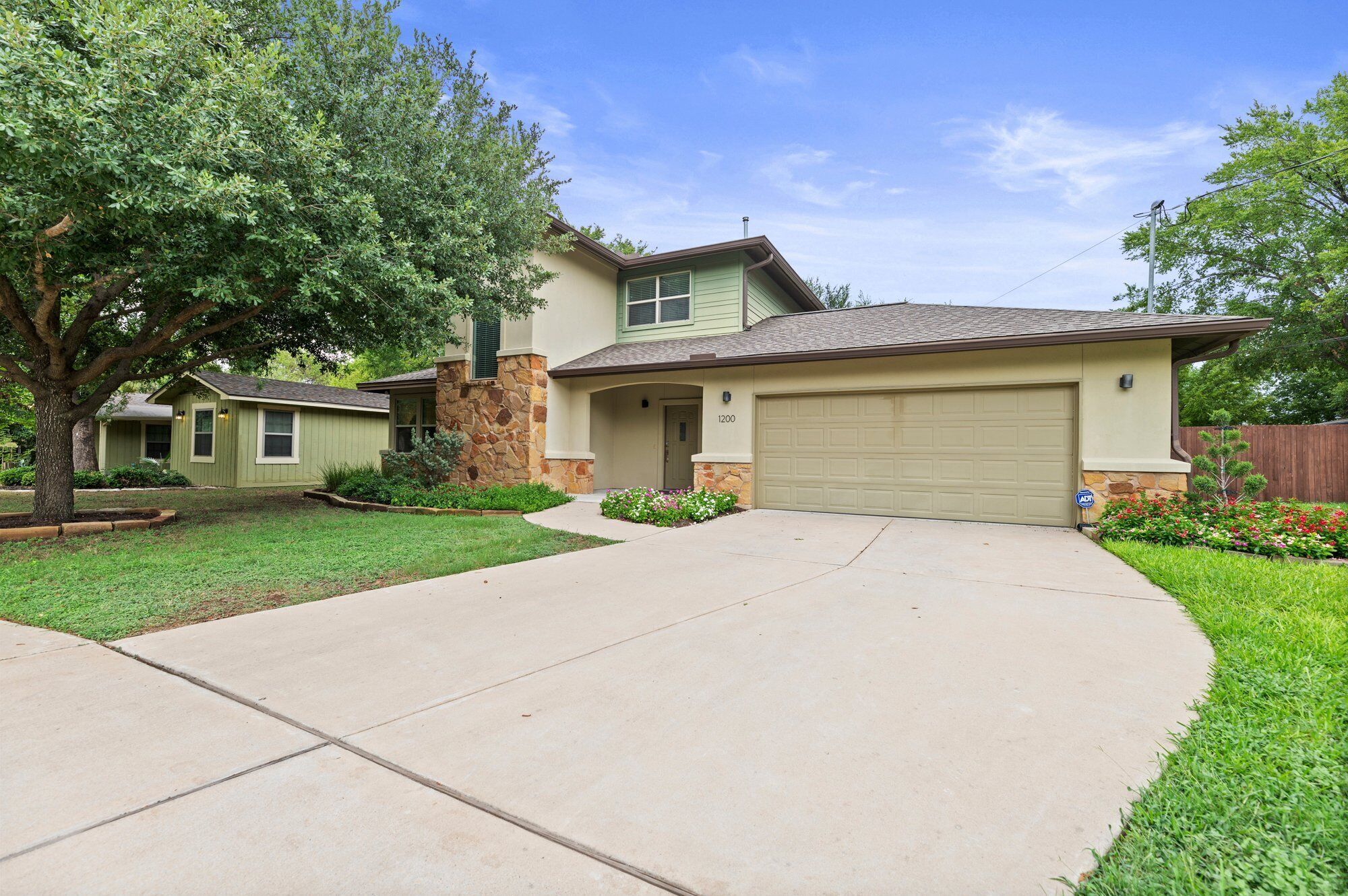 A two-story house with a stone accent wall, a garage, and a well-maintained lawn.