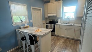 A compact kitchen with a central island, white cabinetry, and a window with blinds. - Captain & Mermaid's Diamond #BP25 (Big Pine Key)