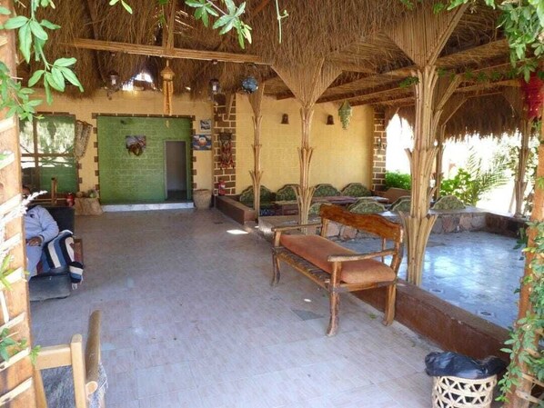 Un espace extérieur abrité, avec des bancs et une porte verte.