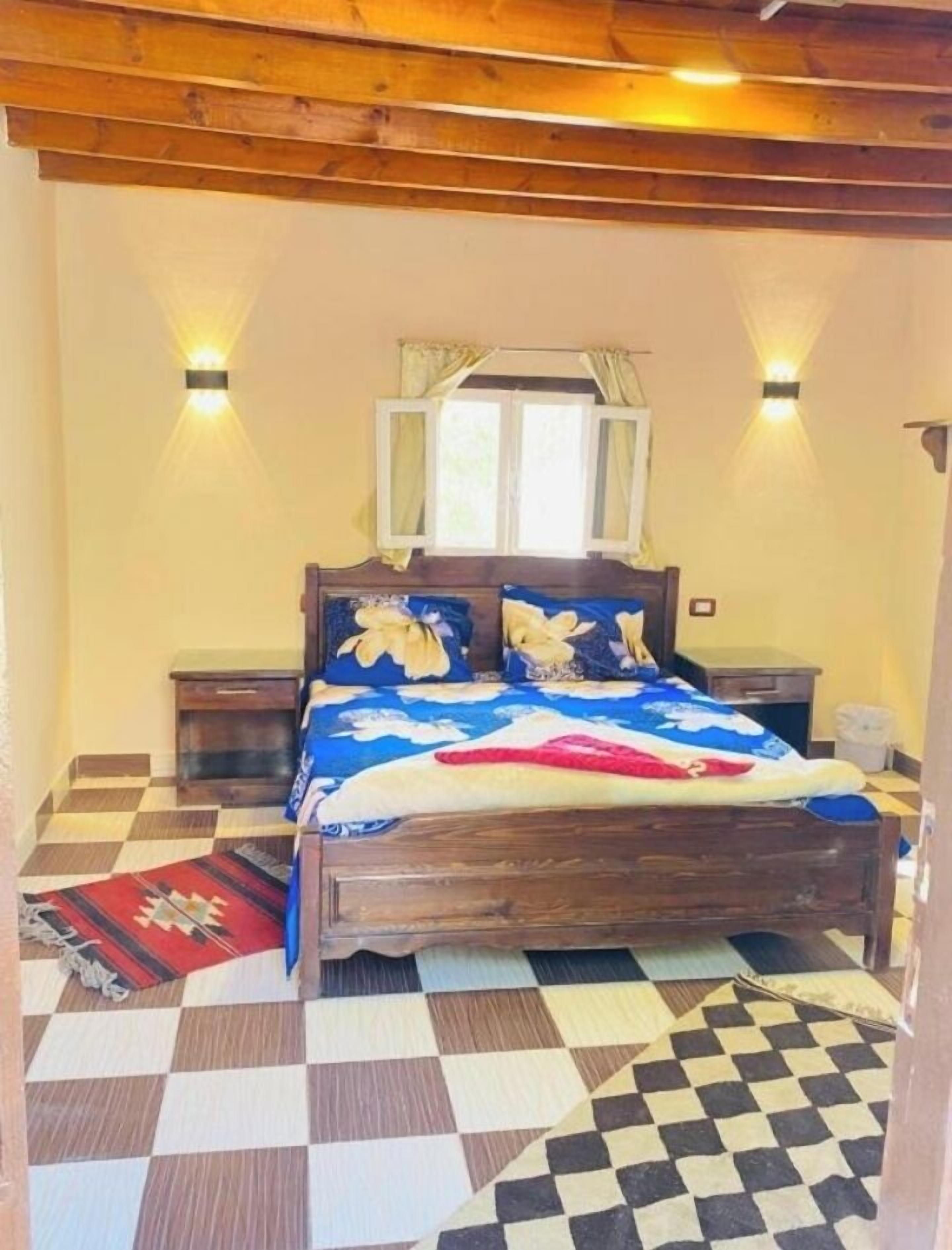 A bedroom with a wooden bed, checkered floor, and two bedside tables.