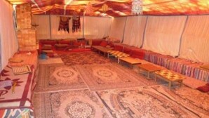 Ein Zimmer mit Teppichmuster, einer Sofagarnitur und einer Pendelleuchte.