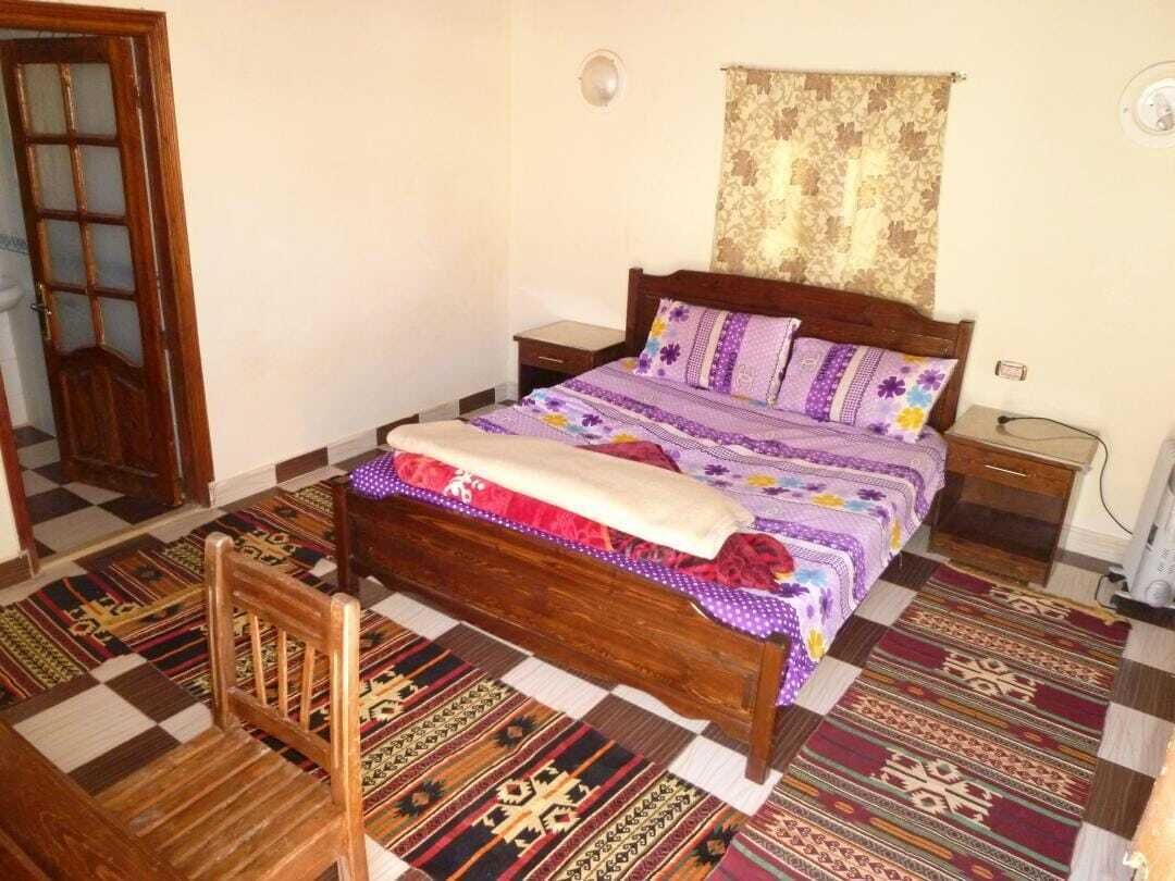 A bedroom with a wooden bed, patterned rugs, and a door.