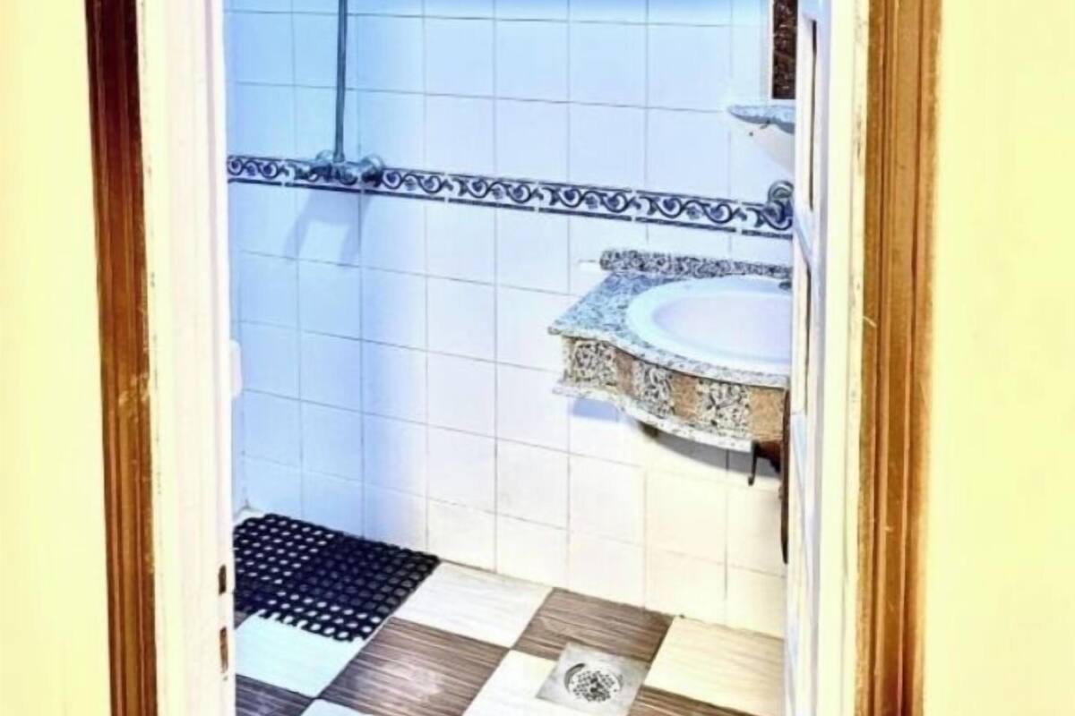 Ein Badezimmer mit Dusche, Waschbecken und einem gemusterten Boden.