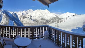 Un balcón cubierto de nieve con vistas a montañas nevadas.