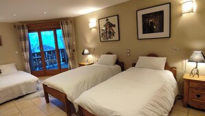 Una habitación de hotel con dos camas, un balcón con cortinas y dos lámparas de pared.