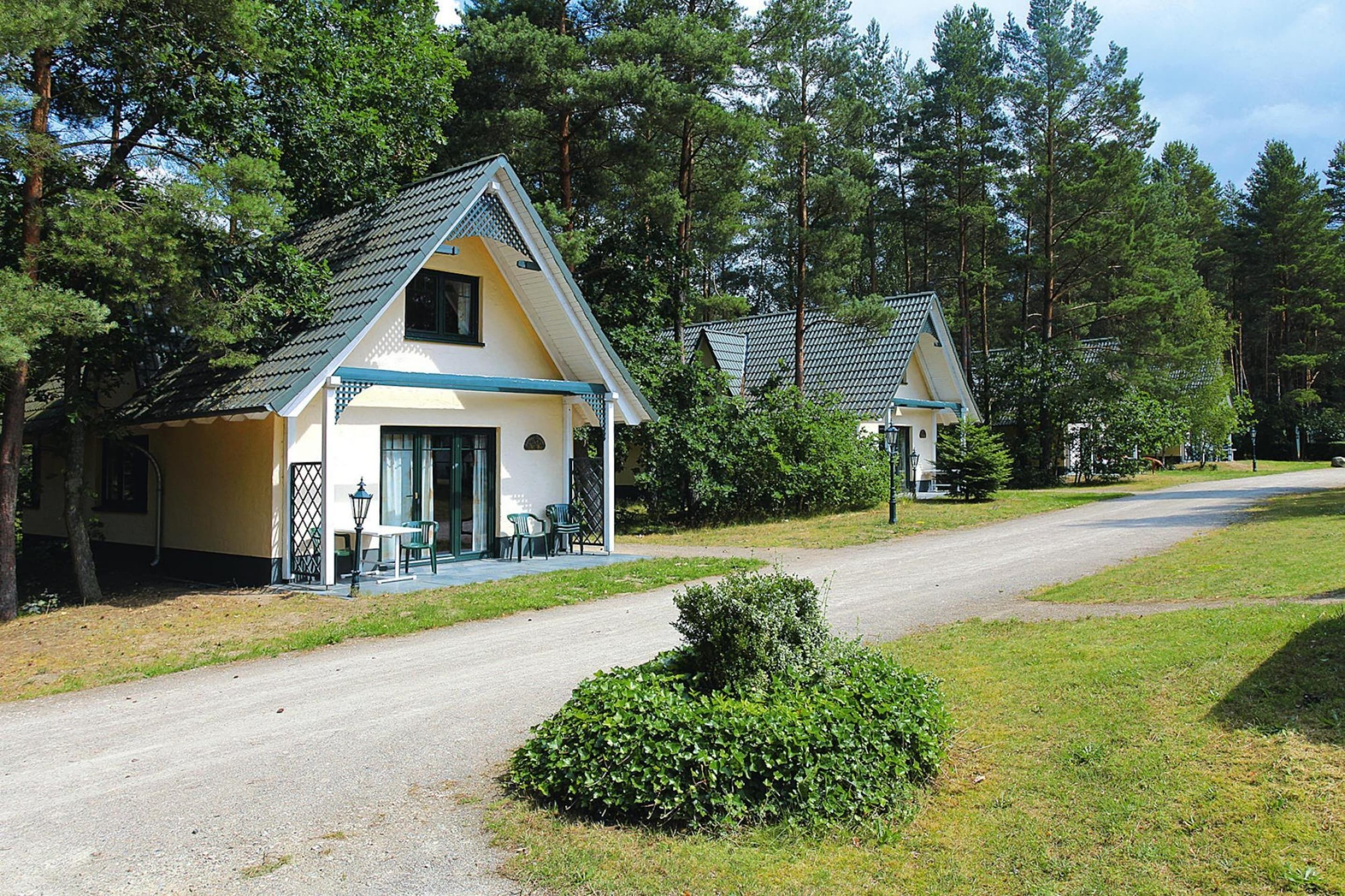 A two-story cabin with a sloped roof, a porch with chairs, and a small garden area.