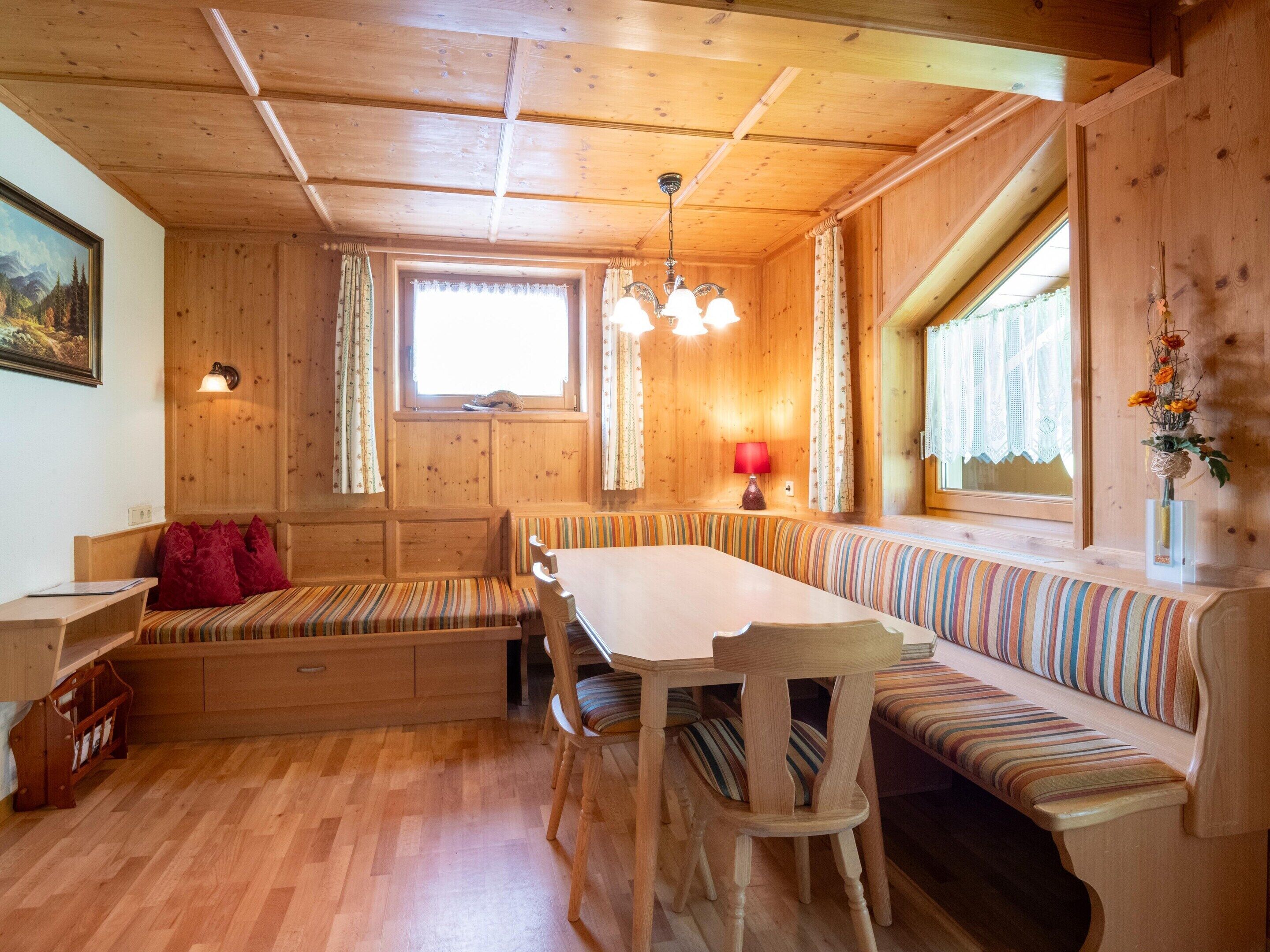 A wooden interior with a dining table, benches, and a window.