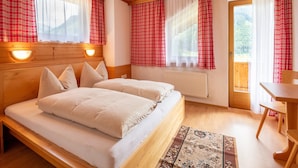 A wooden-paneled room with a bed, two bedside tables, a radiator, and a window with curtains. - Chalet in Mayrhofen Near Ski Slopes (Brandberg)