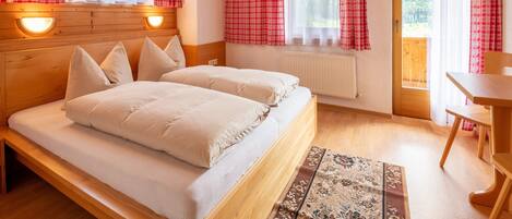 A wooden-paneled room with a bed, two bedside tables, a radiator, and a window with curtains.