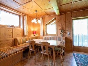 A wooden interior with a dining table, chairs, a bench, and a window with curtains. - Chalet in Mayrhofen Near Ski Slopes (Brandberg)