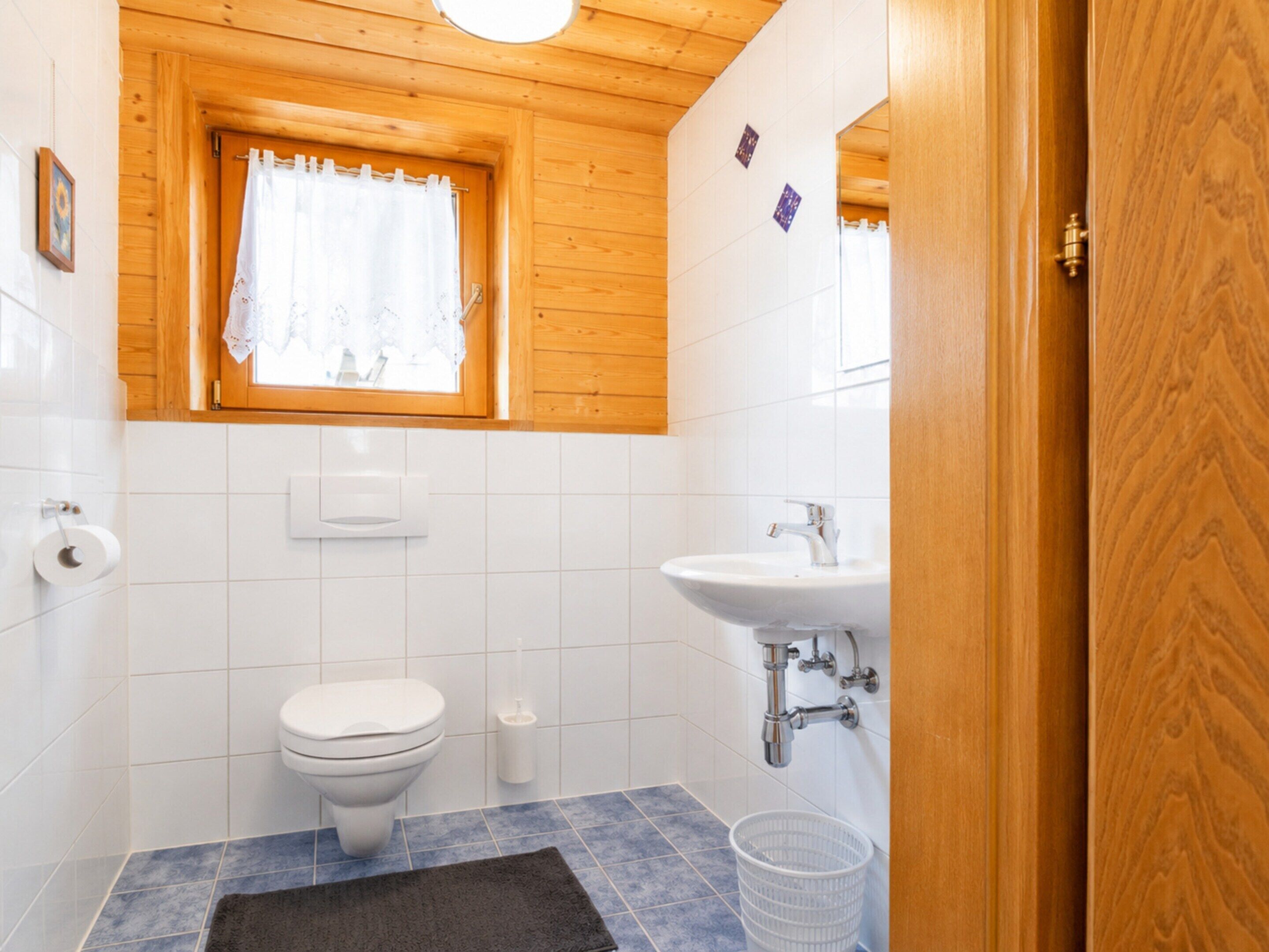 A small bathroom with a toilet, sink, and window.